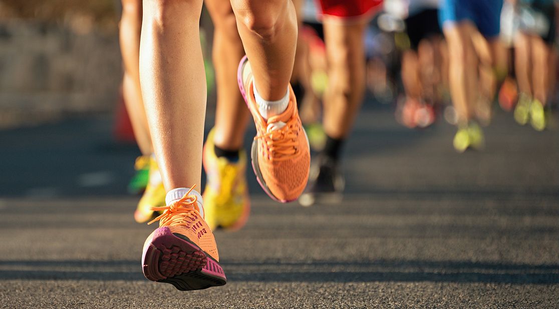 Schmuckbild: Bunte Schuhe von rennenden Läufern auf Asphalt