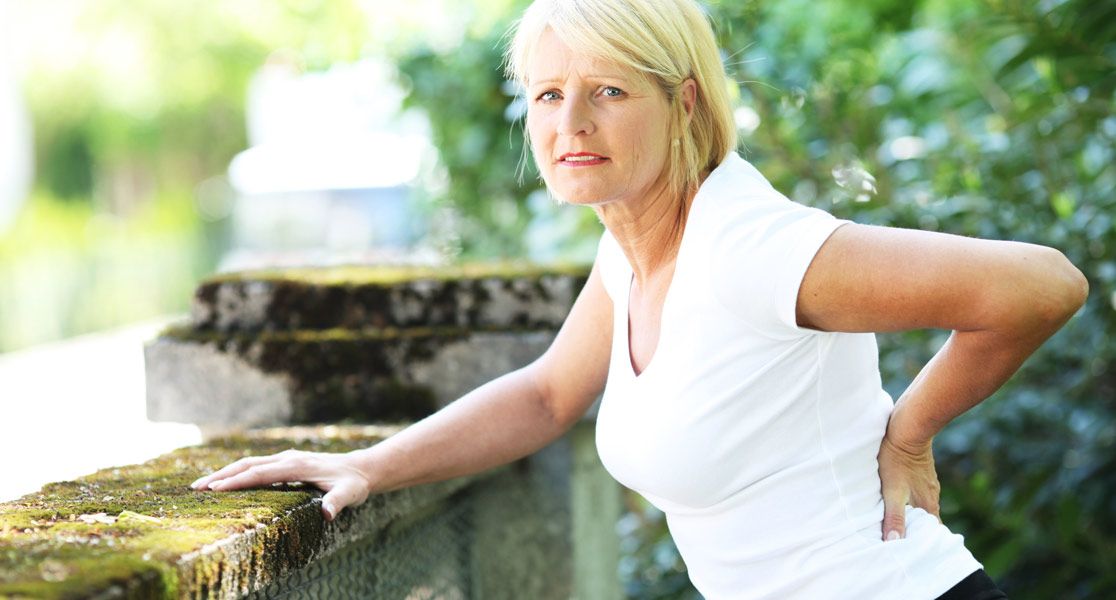Frau fasst sich an ihre Hüfte