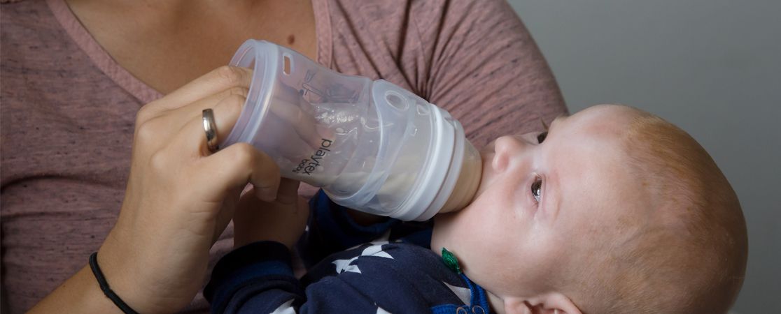 Baby trinkt aus einer Flasche Milch