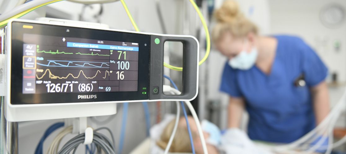 Krankenbett mit Monitor im Hintergrund Pflegekraft und Patient
