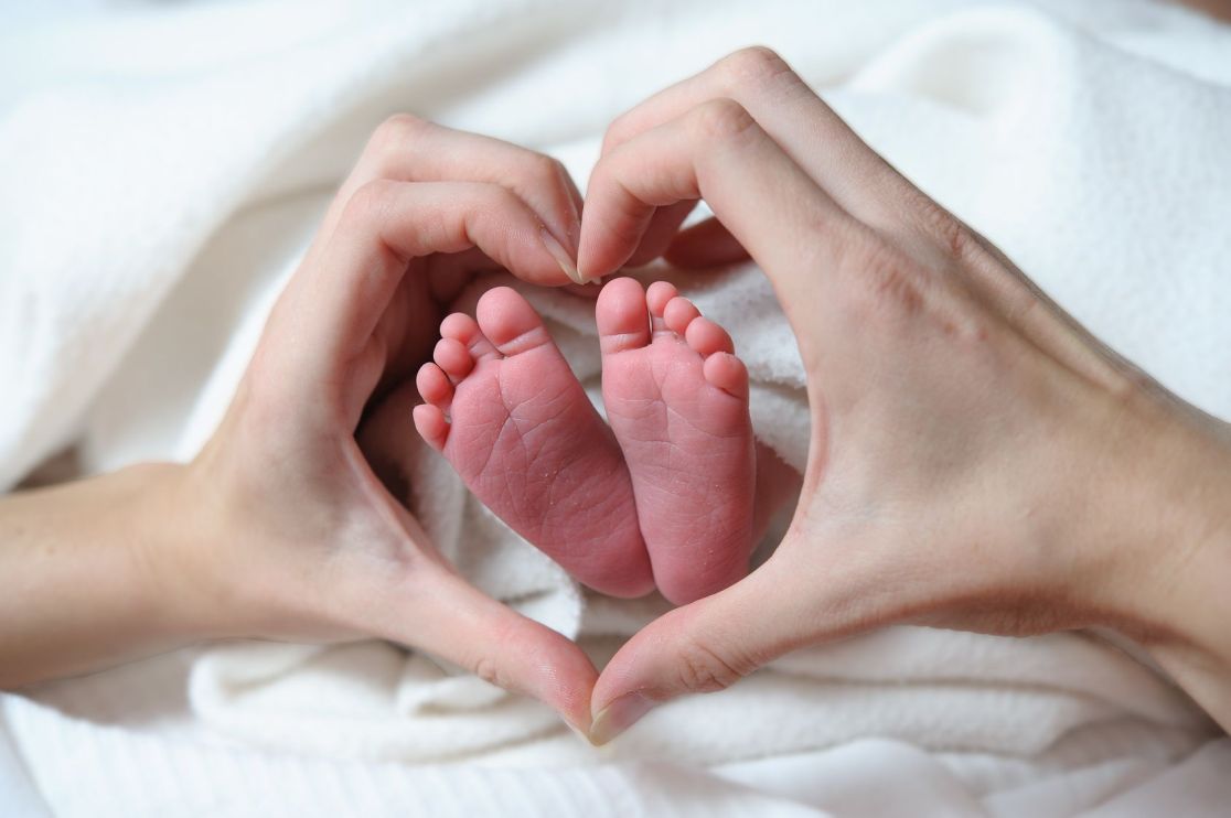 Babyfüße in einem Herz aus Händen