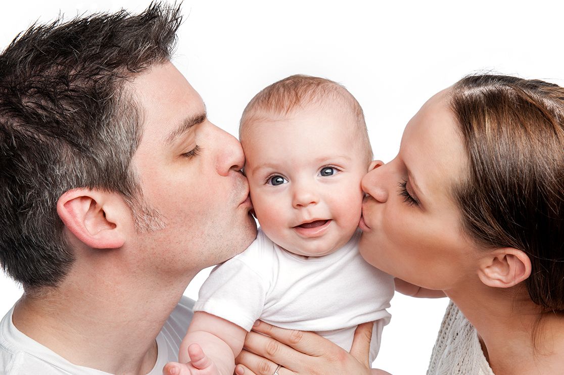 Schmuckbild: Eltern küssen Säugling