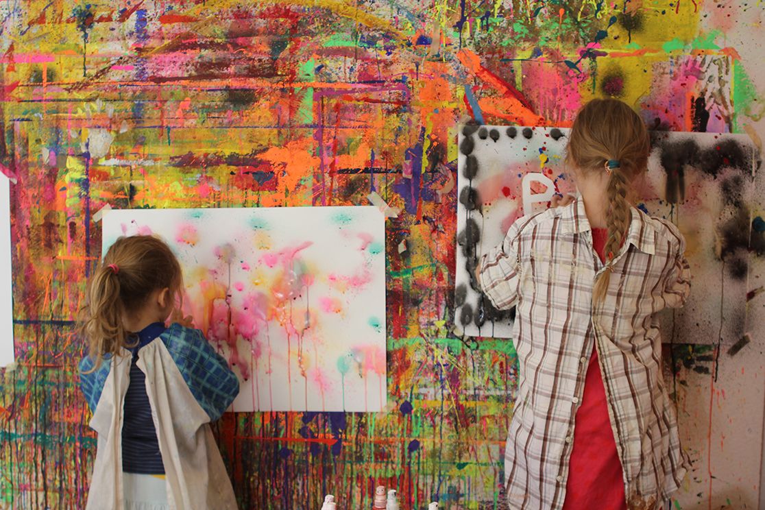 Zwei Mädchen beim Malen an einer bunten Malwand
