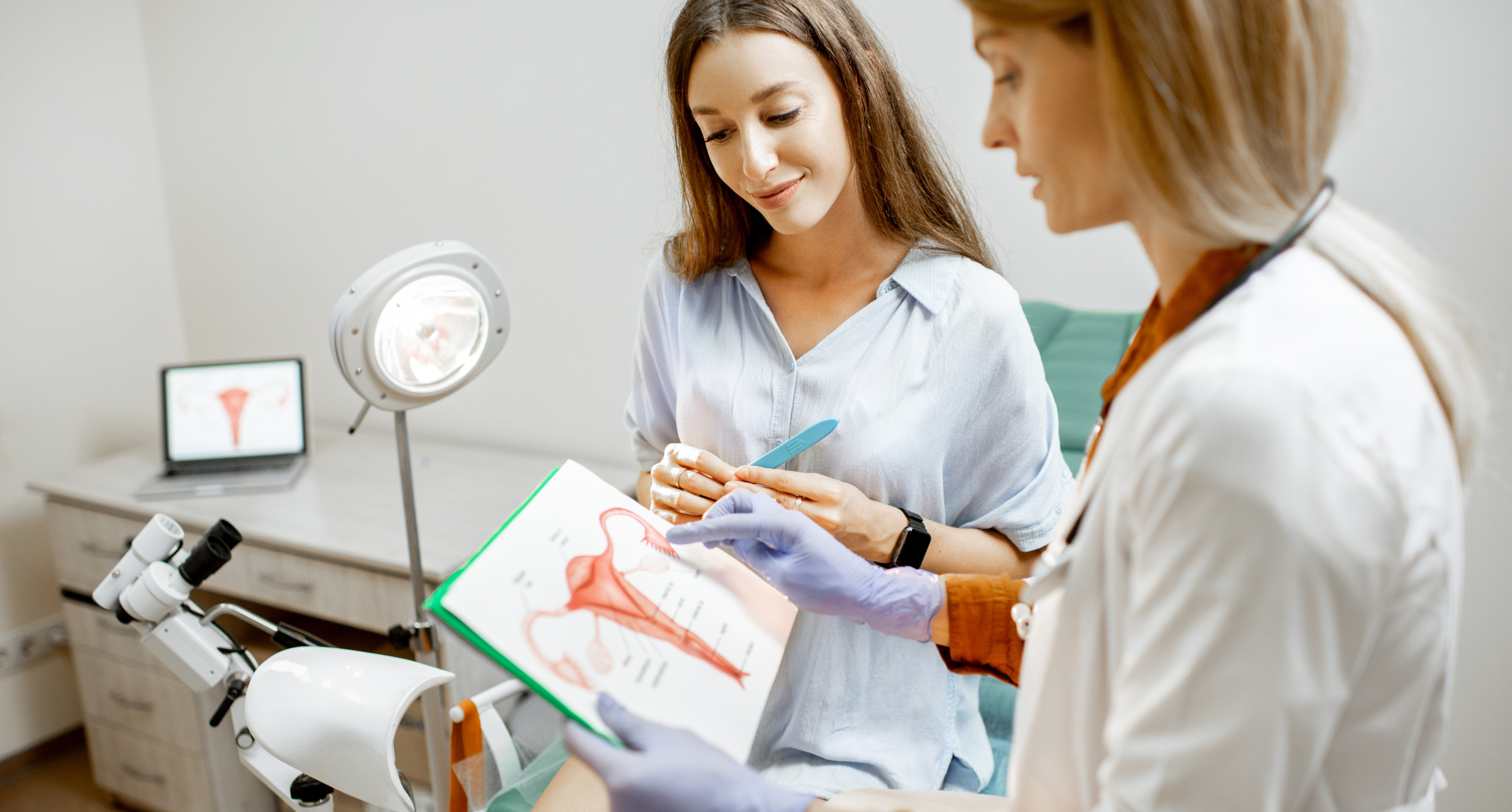 Eine Gynäkologin und eine junge Patientin betrachten gemeinsam eine schematische Darstellung der weiblichen inneren Organe.